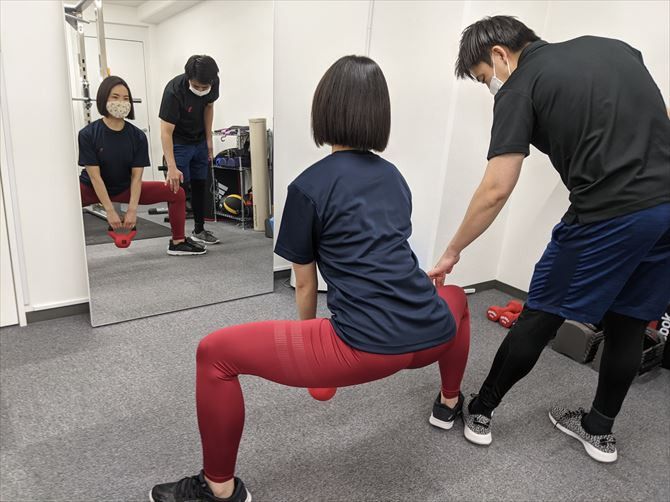 パーソナルジムRat新宿南口店::肩幅より足を広げて、足先は正面から45度に向け、背筋を伸ばして腰をゆっくりおろしていくという動作。回数は10回を2～3セット。膝が内側に入らないようにし、内ももが伸びるように腰を下ろすことを意識して行います。